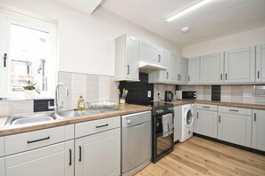 A modern kitchen with white cabinets, a dishwasher, an oven, and a microwave. - Sea Escape - Convenient location (North Yorkshire)