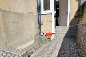 A narrow outdoor corridor with a glass door leading to a room, a red bucket, and a white door in the background. - Sea Escape - Convenient location (North Yorkshire)