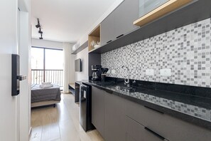 Una cocina moderna con encimera negra, armarios grises y un salpicadero con estampado.