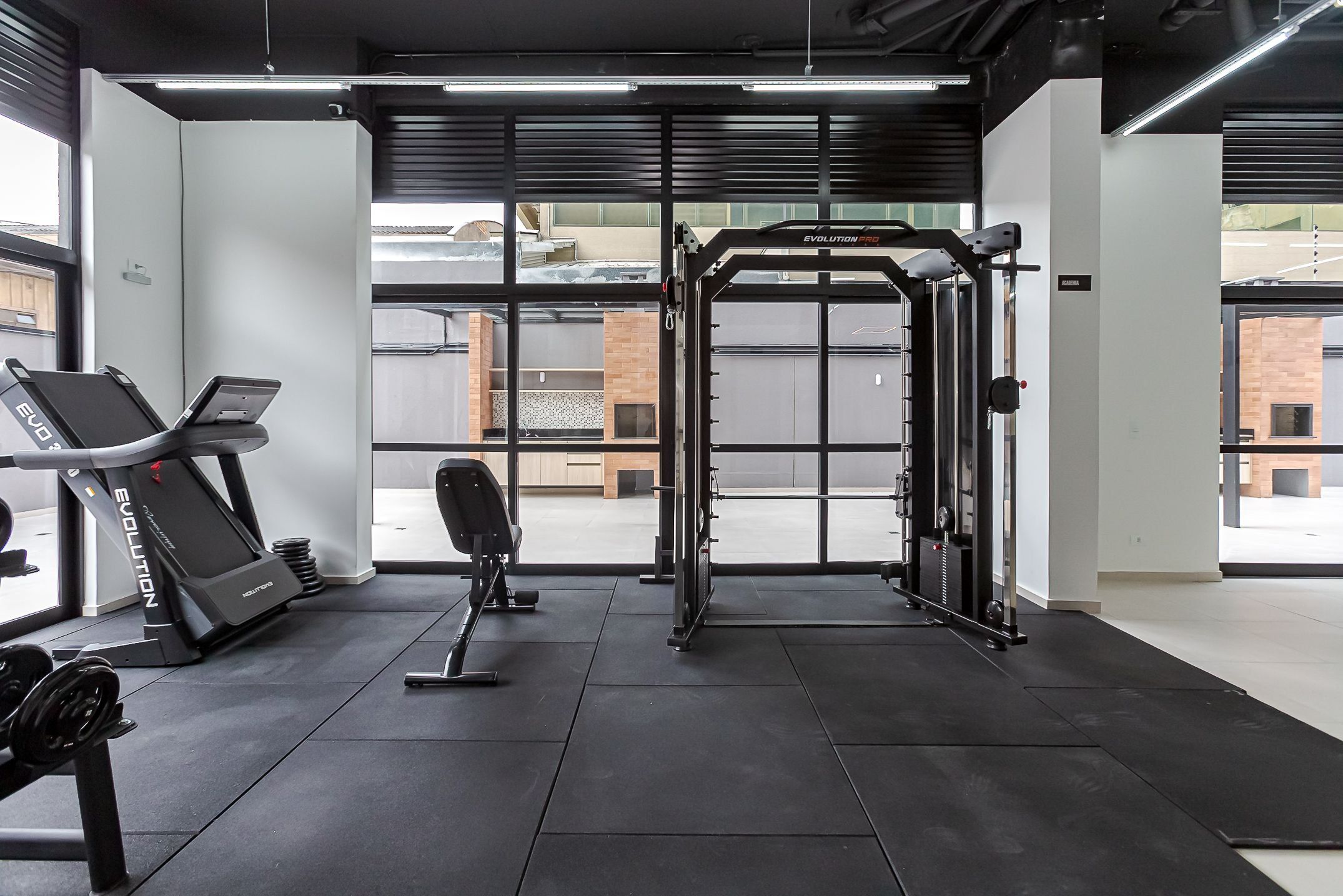 Un gimnasio con equipo de ejercicio, incluyendo cintas de correr y una estructura para sentadillas.