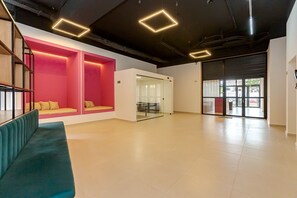 A spacious room with a teal sofa, a pink seating area, and a glass door leading to an outdoor area. - ROC Curitiba by Housi (Curitiba)