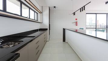 Cozinha moderna com bancada ampla, armários e vista para a cidade através de grandes janelas.
