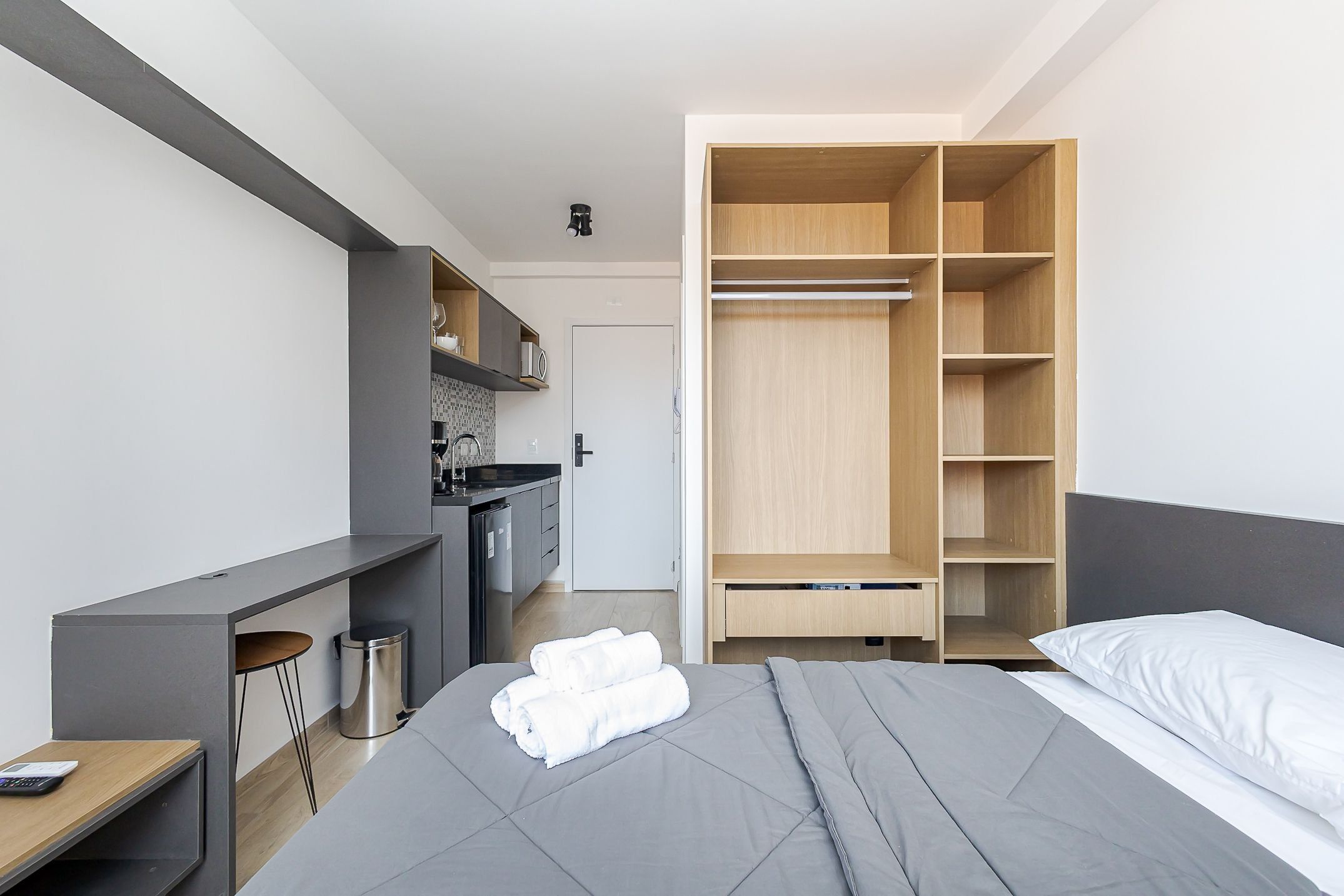 Una habitación de hotel moderna con cama, escritorio, armario y kitchenette.