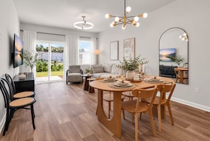 Un espace de repas moderne avec une table en bois dressée pour quatre personnes, un canapé et une chaise en arrière-plan.
