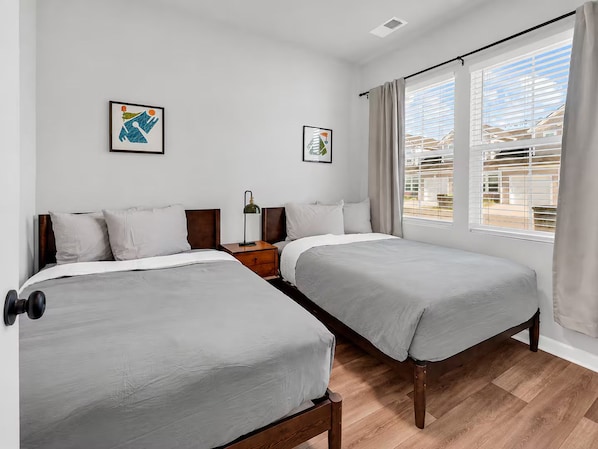 Habitació d'hotel amb dos llits, una taula de nit, una làmpada i obres d'art a les parets.