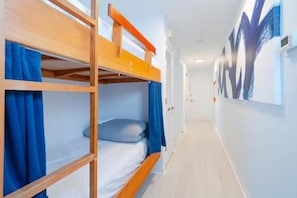 Ein Korridor mit Stockbetten, einer Tür am Ende und einer Wand mit einem großen abstrakten Gemälde.