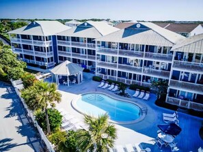 Ein Hotel mit mehreren Balkonen, einem Schwimmbad und Liegestühlen.