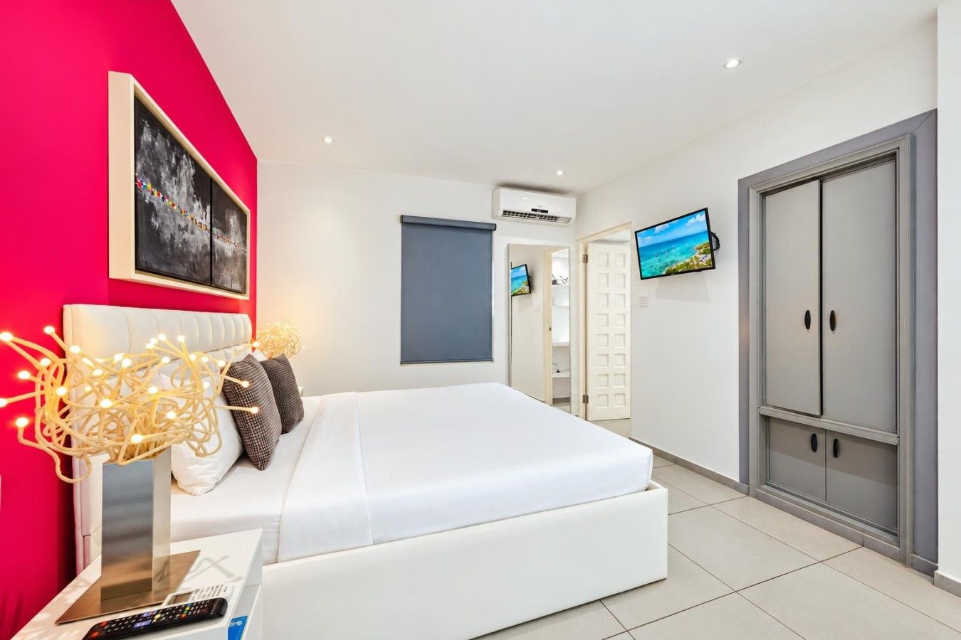 Unwind in a cozy, air-conditioned bedroom with soft bedding, beautiful artwork, a wall-mounted TV, and ample storage.
