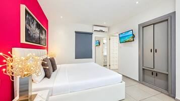 Unwind in a cozy, air-conditioned bedroom with soft bedding, beautiful artwork, a wall-mounted TV, and ample storage.