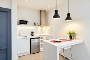 Enjoy a bright, modern kitchenette with sleek appliances, a dining counter, elegant pendant lights, and a cozy atmosphere.