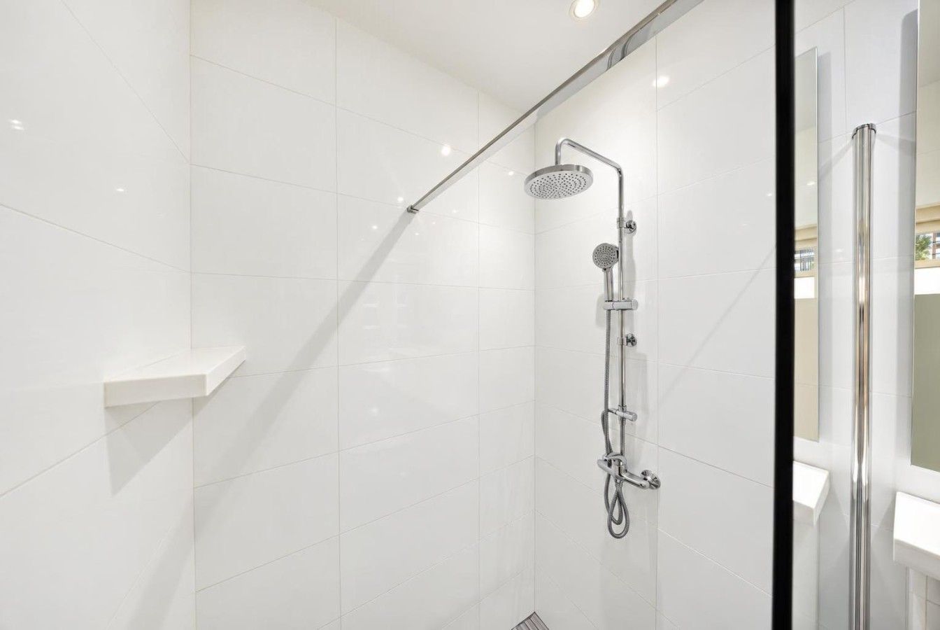 Refresh in a sleek, modern walk-in shower featuring a rainfall showerhead, handheld shower, and elegant white tiles.