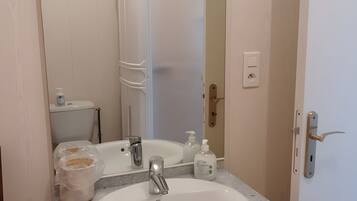 Une salle de bain avec un lavabo blanc, un miroir et des toilettes.