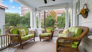 A covered porch with wicker furniture and a ceiling fan.