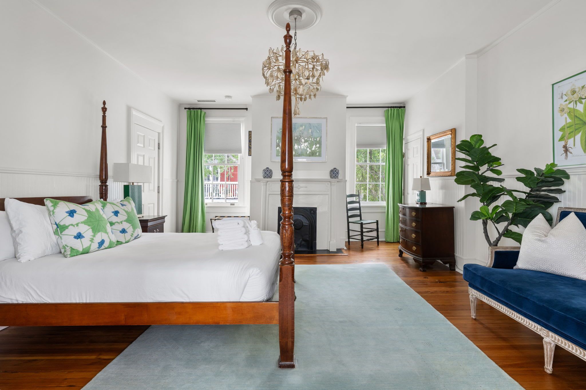 Ein Schlafzimmer mit Himmelbett, einer Chandelüster, einem blauen Sofa und einem Kamin.