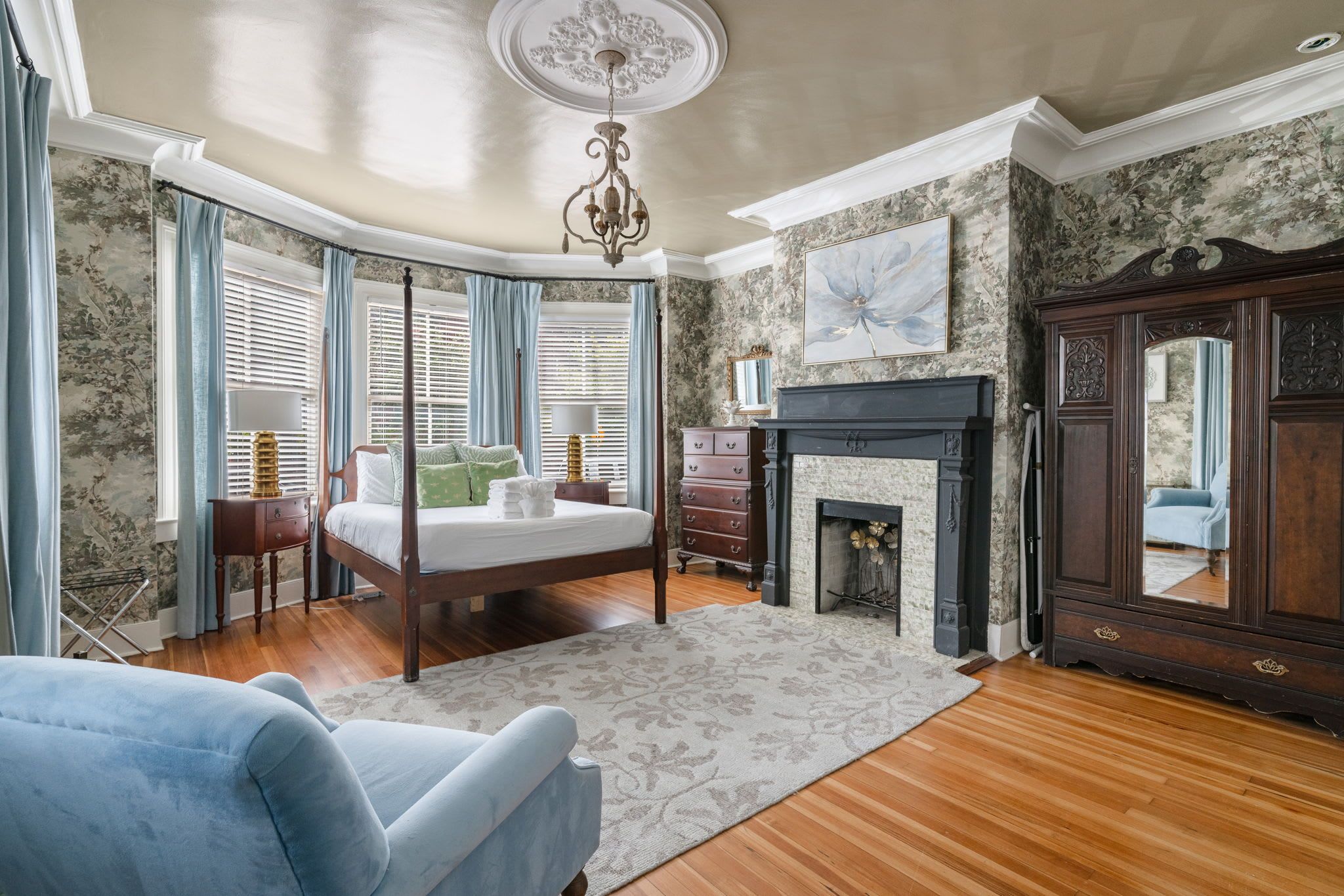 A bedroom with a four-poster bed, a fireplace, and a large mirror.