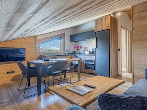 Una cocina moderna con armarios de madera, horno empotrado y ventana con vistas al paisaje.