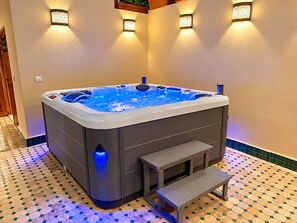 Un jacuzzi con panel de control, un escalón y un banco.