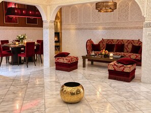 A luxurious interior with a dining area, a fireplace, a sofa set, and a decorative gold vase. - Palais Tedya (Marrakech)