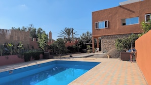 A swimming pool with a clear blue water surface, surrounded by a paved area with a patterned tile design.