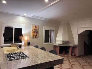 A kitchen with a granite countertop, gas stove, and a fireplace.