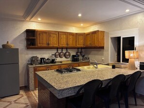 A kitchen with granite countertops, wooden cabinets, a gas stove, and a sink. - Vrbo Property (Lagfifat)