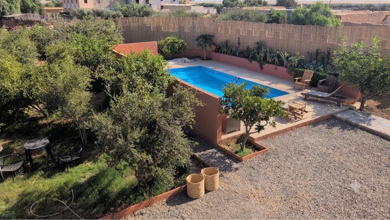 A swimming pool surrounded by greenery, with outdoor seating and a clear view of the surrounding landscape.