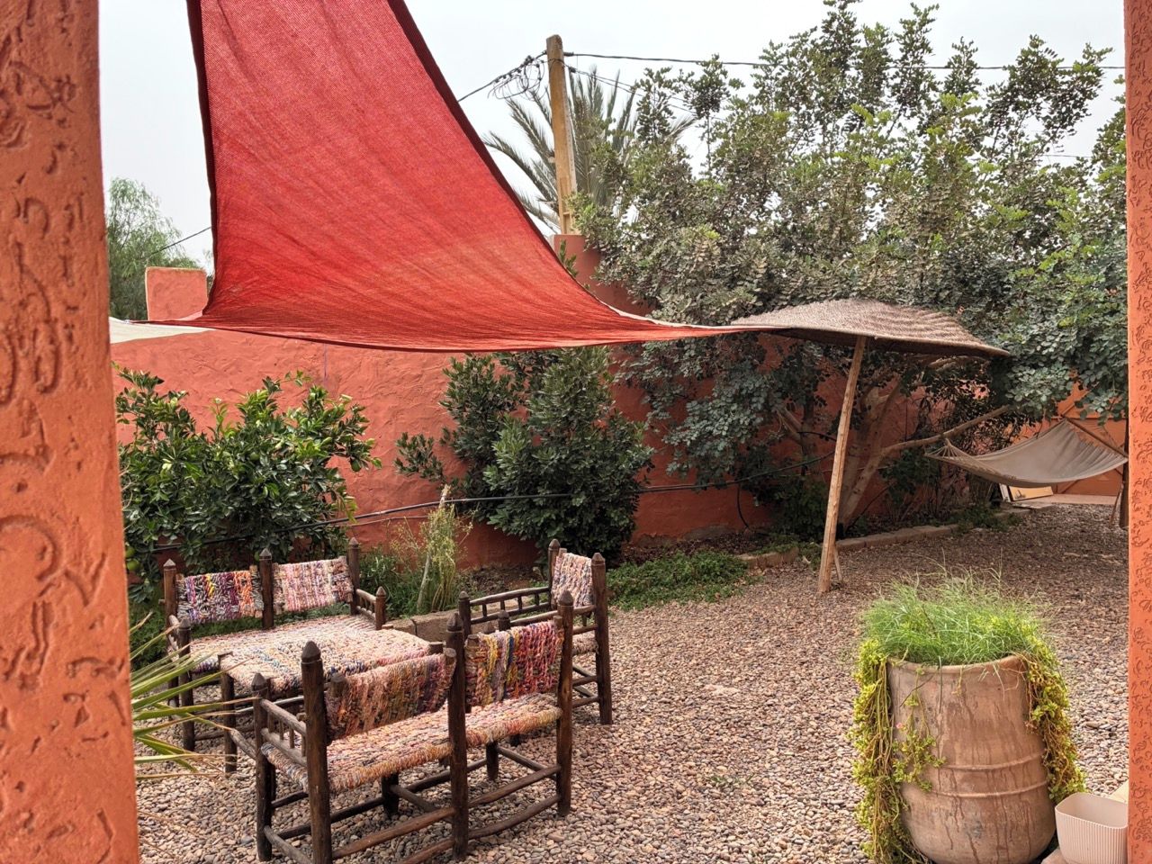 Un espacio al aire libre con mesa y sillas, una vela roja y una planta en maceta.