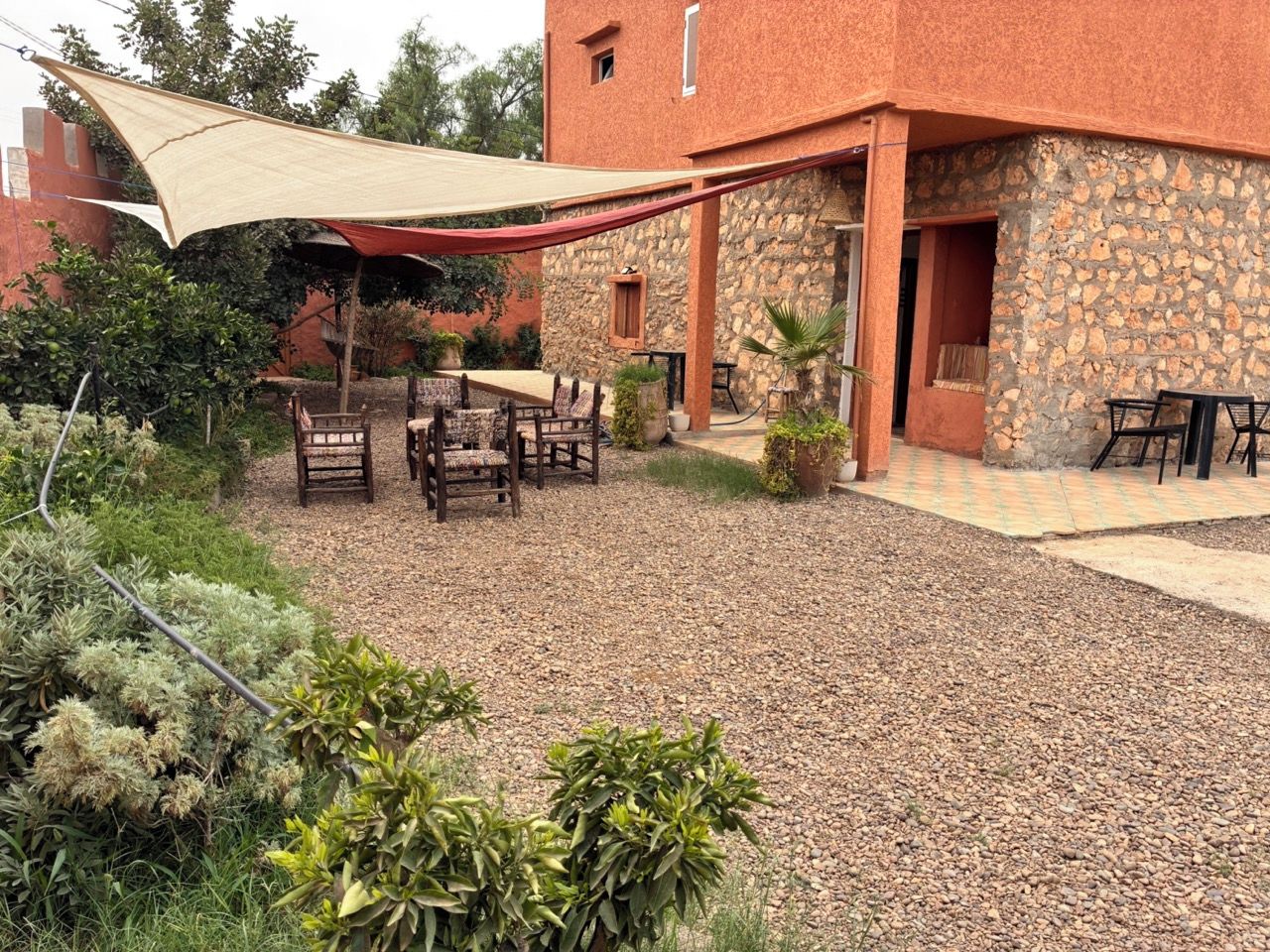 A patio area with outdoor furniture, a stone building, and a large shade sail.