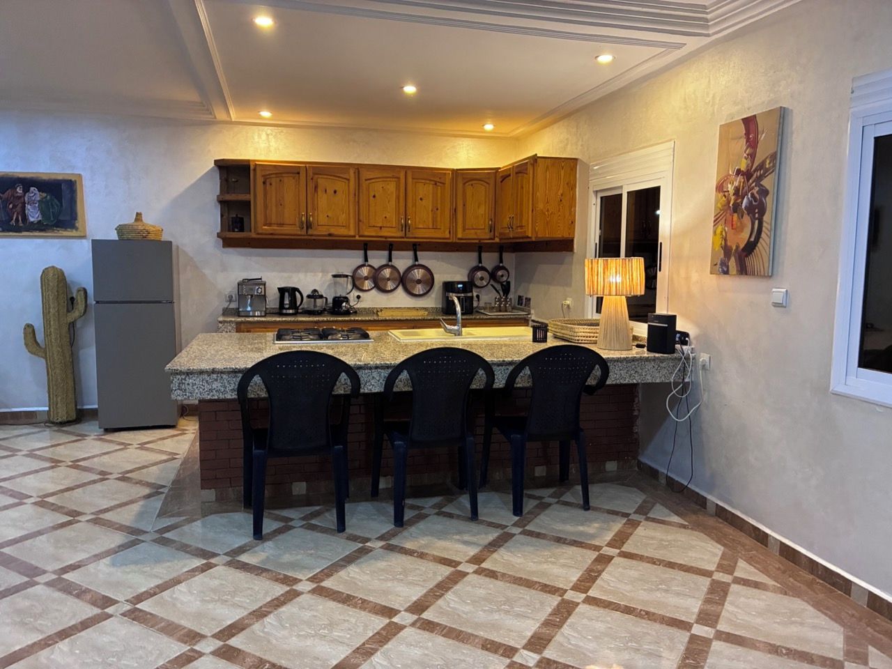 Una cocina con armarios de madera, encimera de granito e isla integrada con taburetes de bar.