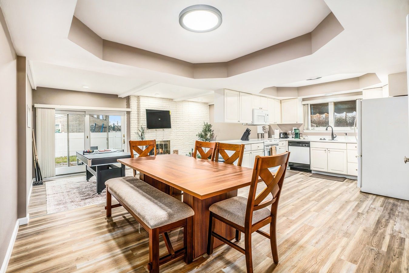 Una cocina moderna con comedor, muebles de madera y televisor de pantalla plana.