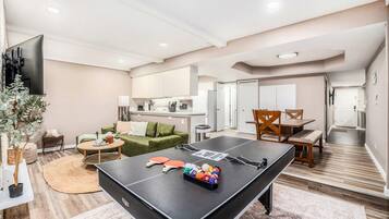 Una sala moderna con mesa de ping pong, sofá, mesa de centro y comedor con sillas.