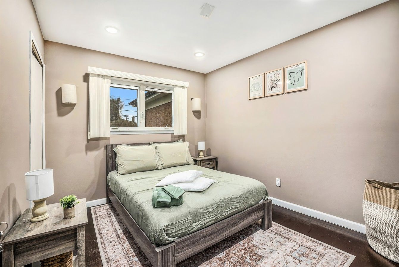 Un dormitorio con cama, mesitas de noche, una ventana y una lámpara fijada a la pared.