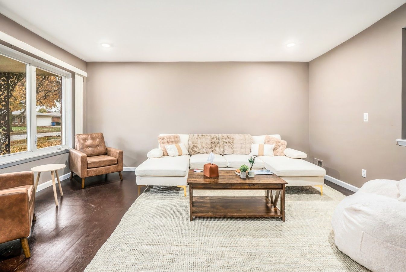A living room with a sofa, armchairs, a coffee table, and a large window.