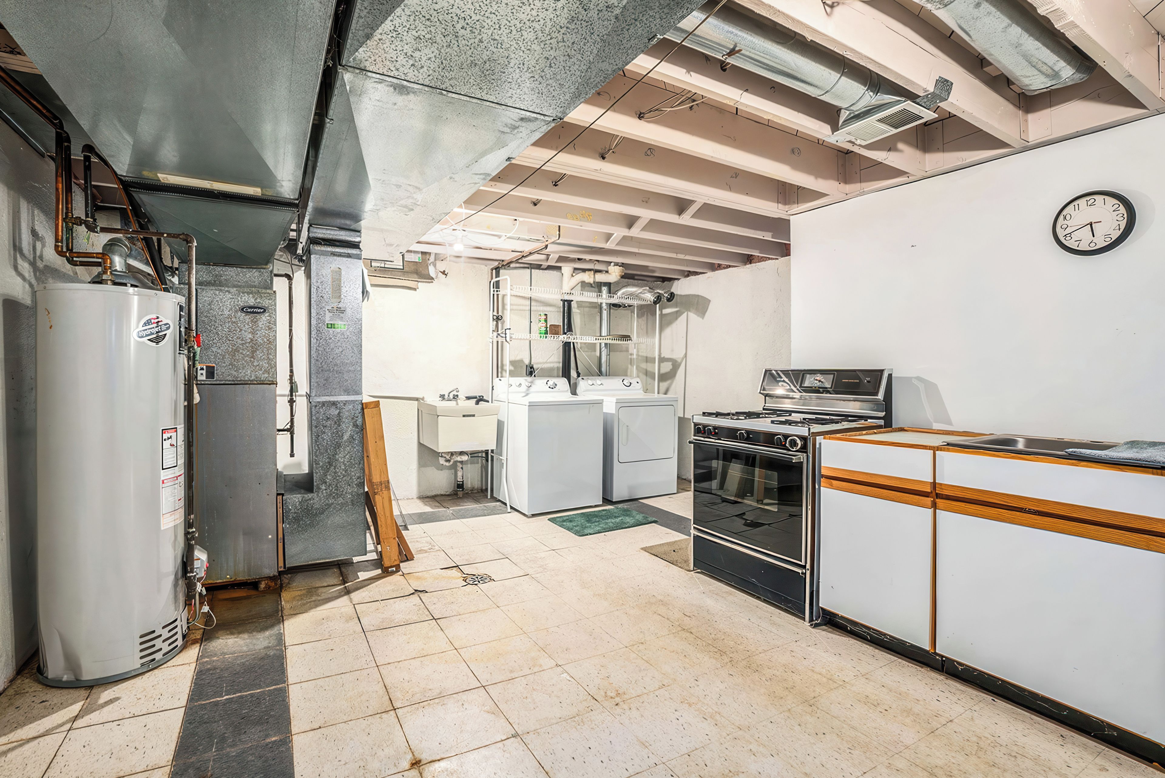 A kitchen with a refrigerator, stove, sink, and a clock on the wall.