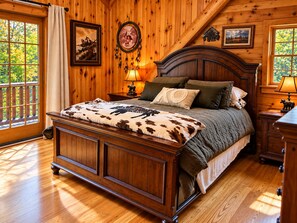 A wooden-paneled bedroom with a large bed, a nightstand, a lamp, and a window with a view of trees. - Harriman Reservoir Log Cabin- 10 Min to Mount Snow (Wilmington)