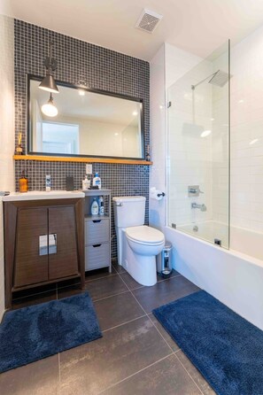 A modern bathroom with a glass shower enclosure, a large mirror, and a dark wood vanity. - Prime Greenpoint 3BR • Balcony • Park View (Brooklyn)