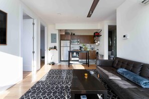 A modern living room with a sofa, coffee table, and a patterned rug. - Prime Greenpoint 3BR • Balcony • Park View (Brooklyn)