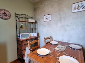 A dining area with a wooden table set for two, a vintage radio, and a wall clock. - Comfortable house, pets allowed - 6 guests (SAINT CYPRIEN)