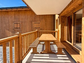 A wooden deck with a table and benches, surrounded by wooden walls and a glass door. - Charming apartment, parking - 6 guests (Champagny-en-Vanoise)