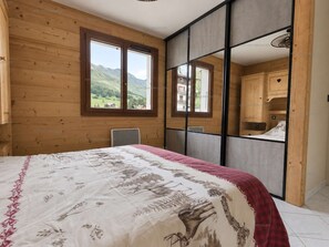 Ein Schlafzimmer mit Bett, Fenster und Blick ins Freie.