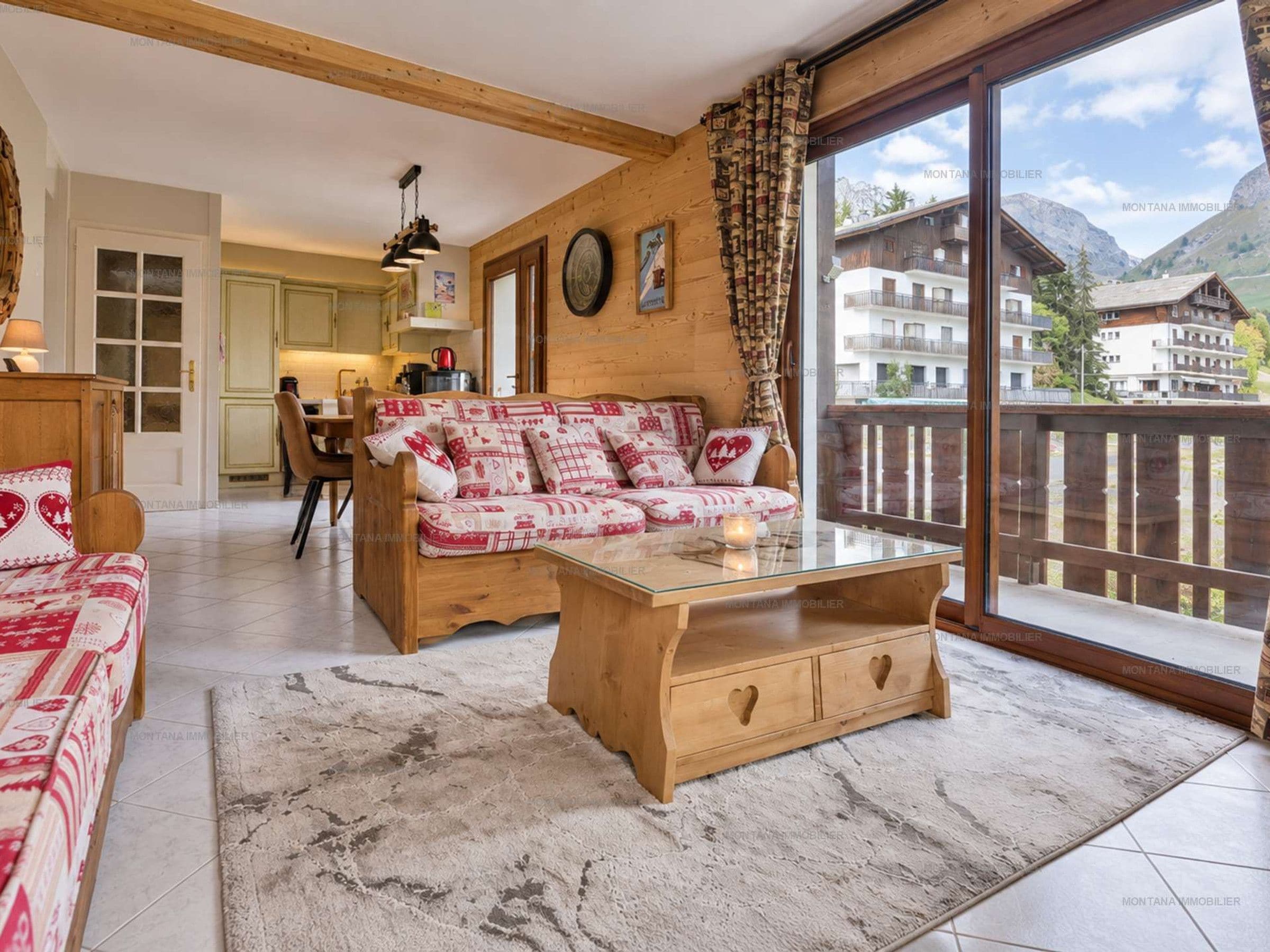 A cozy living room with a sofa, a coffee table, and a view of a mountain landscape.