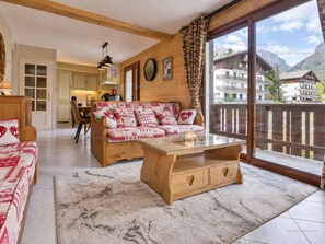 A cozy living room with a sofa, a coffee table, and a view of a mountain landscape. - Apartment with parking - 6 guests, mountain view (Le Grand-Bornand)