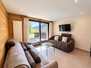 Ein modernes Wohnzimmer mit einer Couch, einem Couchtisch und einem Flachbildfernseher.