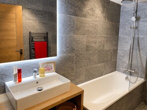 A bathroom with a white sink, a shower, and a wooden vanity. - Ideal apartment at the slopes - 6 guests (Huez)