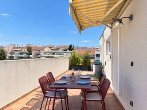 Una terrazza con tavolo apparecchiato per mangiare, illuminazione esterna e vista sulla città.