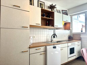 A kitchen with white cabinets, a dishwasher, a sink, and a window with a view of the outside. - Air-conditioned apartment, stunning views - 2 guests (Hyères)