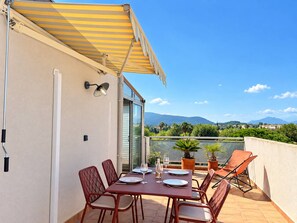 A terrace with a table set for dining, outdoor chairs, and a view of the landscape. - Air-conditioned apartment, stunning views - 2 guests (Hyères)