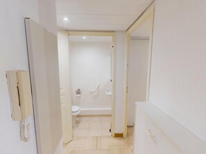 Ein schmaler Flur, der zu einem Badezimmer mit Toilette und Waschbecken führt.
