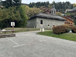A stone building with a sign reading 'L'OURSON' in front of a forested hillside. - Semi-detached chalet, mountain view - 6 guests (Méribel)