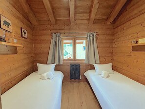 A cabin with two beds, wooden walls, a window with curtains, and a radiator. - Semi-detached chalet, mountain view - 6 guests (Méribel)